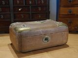 a brown suitcase sitting on a wooden floor next to a dresser