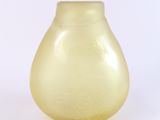 un vase jaune posé sur une surface blanche