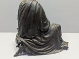 statue of a woman sitting on the ground with her back to the camera