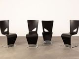 three black chairs sitting on top of a cement floor next to a white wall