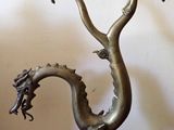 une sculpture en métal représentant un dragon, posée sur une table avec deux bougies