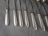 a lot of silverware on a table with silver spoons and knives