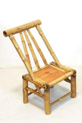 une petite chaise faite de tiges de bambou posée sur un sol blanc