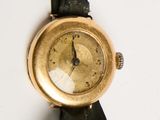 a gold wrist watch with a black band on a white surface