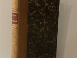 un livre marron posé sur une étagère, près d'un mur blanc