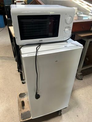 un micro-ondes posé sur un réfrigérateur dans une pièce
