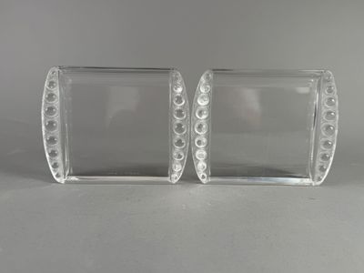 une paire de vases en verre transparent, percés de petits trous, posés sur une table