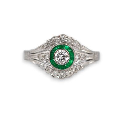 a close up of a diamond and emerald ring on a white background