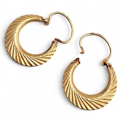 une image représentant une paire de boucles d'oreilles créoles en or sur fond blanc