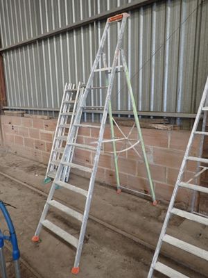 several ladders leaning up against a wall in a warehouse
