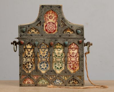 an old metal box with decorative designs on it sitting on a table