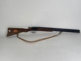un fusil posé sur un socle en bois, sur fond blanc