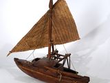 un petit bateau en bois muni d'une voile en paille