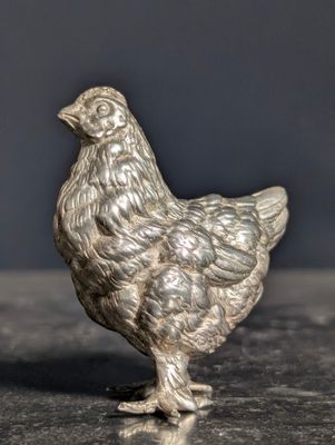 a silver figurine of a chicken on a table