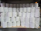 Plusieurs rouleaux de papier toilette sont empilés sur une étagère dans un entrepôt