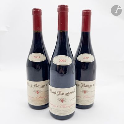 trois bouteilles de vin rouge sont alignées sur une surface blanche