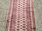 un tapis rouge et blanc posé sur un sol recouvert de gravier