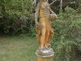 une statue représentant une femme debout dans l'herbe