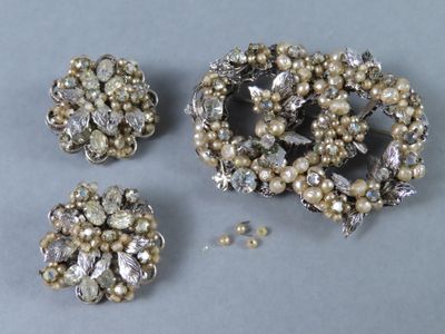 trois broches en argent et en perles posées sur un fond gris