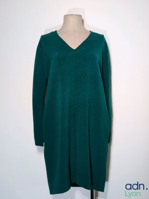 La robe est verte, avec un col en V et des manches longues.