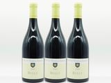 trois bouteilles de vin rouge posées l'une à côté de l'autre sur une surface blanche