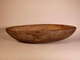 a large wooden bowl sitting on a table next to a cup