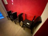 trois chaises noires alignées contre un mur rouge