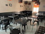 Des tables et des chaises sont disposées dans un restaurant aux murs noirs.
