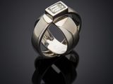a close up of a ring with a diamond on a black surface