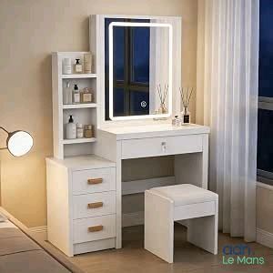 une coiffeuse blanche avec un miroir et un tabouret, placée devant une fenêtre