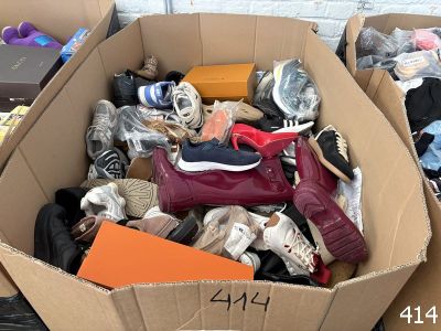 une boîte en carton remplie de chaussures et des chaussures par terre