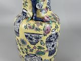 a yellow vase with blue and white flowers on it
