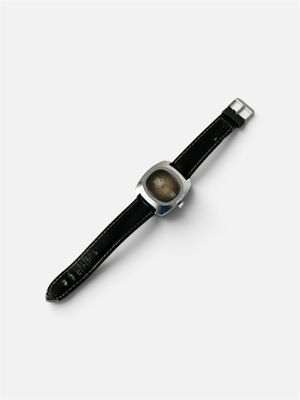 une photo d'une montre posée sur une surface blanche, avec un bracelet noir