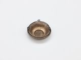a small metal bowl with a handle on a white surface