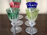 several different colored wine glasses sitting on top of a wooden table