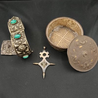 trois bijoux en argent et en turquoise posés sur un fond noir