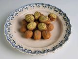 une assiette posée sur une table, sur laquelle se trouvent des noix et des noisettes