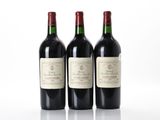 three bottles of wine are lined up on a white surface
