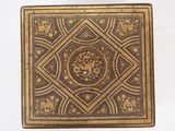 une vieille boîte ornée de motifs dorés et noirs sur fond blanc