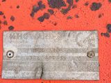 a metal plaque on the side of an orange piece of machinery