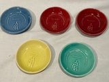 quatre assiettes de couleurs différentes posées sur une table recouverte d'une nappe blanche