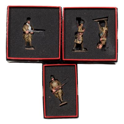 three miniature figurines of soldiers in red boxes on a white surface