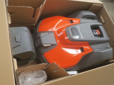 une tondeuse à gazon orange et grise rangée dans un carton