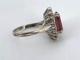 a close up of a silver ring with a red stone