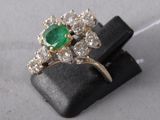 an image of a green and white diamond ring sitting on top of a black piece of wood