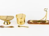 three brass objects including a scale, spoon, spoon and spoon rest