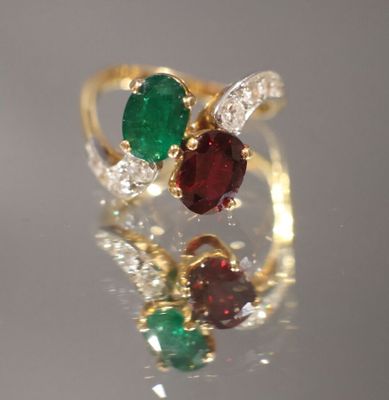 une image montrant un gros plan d'une bague en or sertie d'une pierre verte et rouge