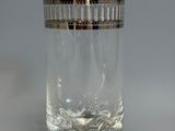 une image représentant un verre transparent muni d'un couvercle argenté, posé sur une surface grise
