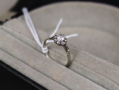 une bague posée dans une boîte entourée d'un ruban
