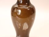 a brown vase that is sitting on a white surface